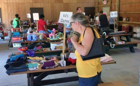 a community yard sale day with people perusing the stands