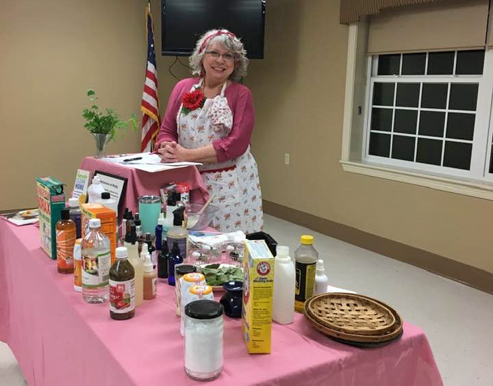 woman standing at a table with natural cleaning products on display