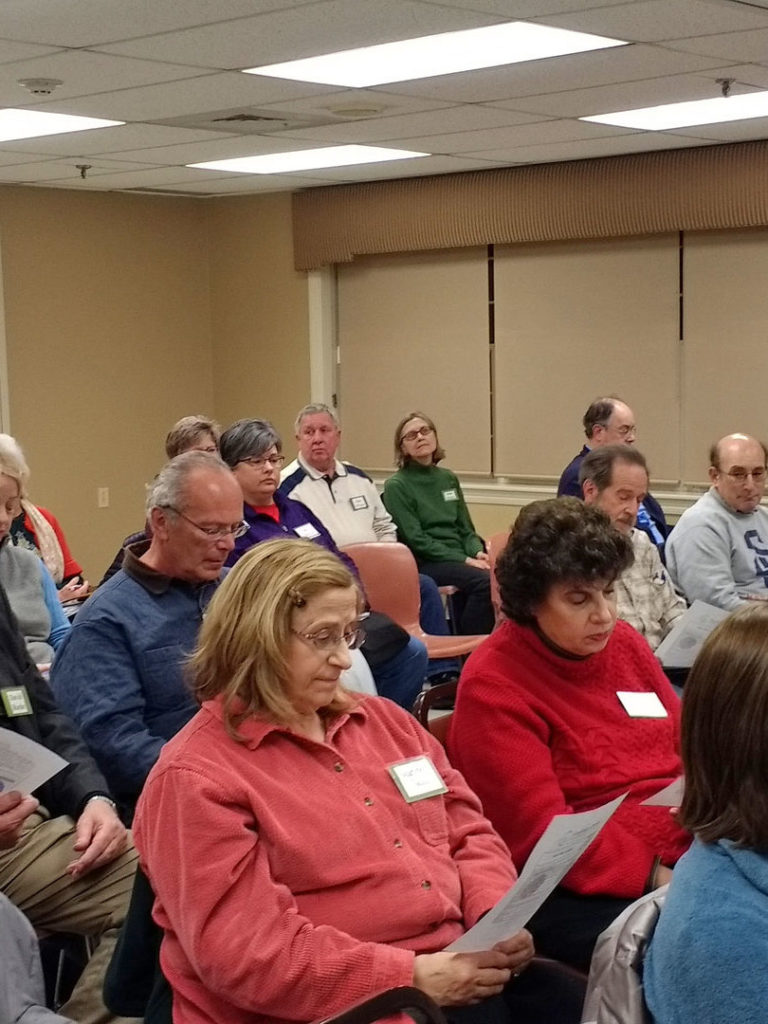 a group of people reading pamphlets at a community meeting